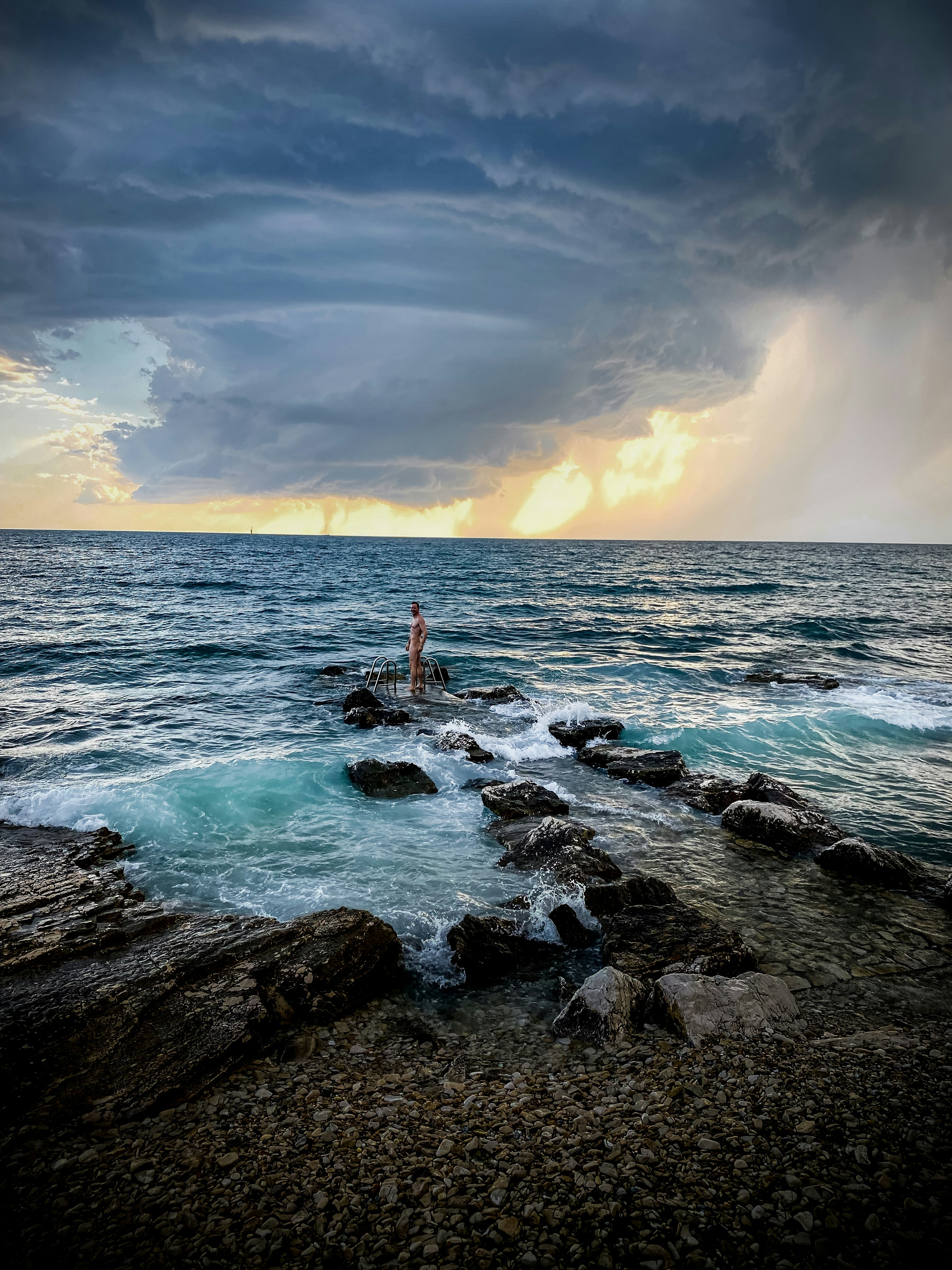 person standing on rock formation in sea during daytime